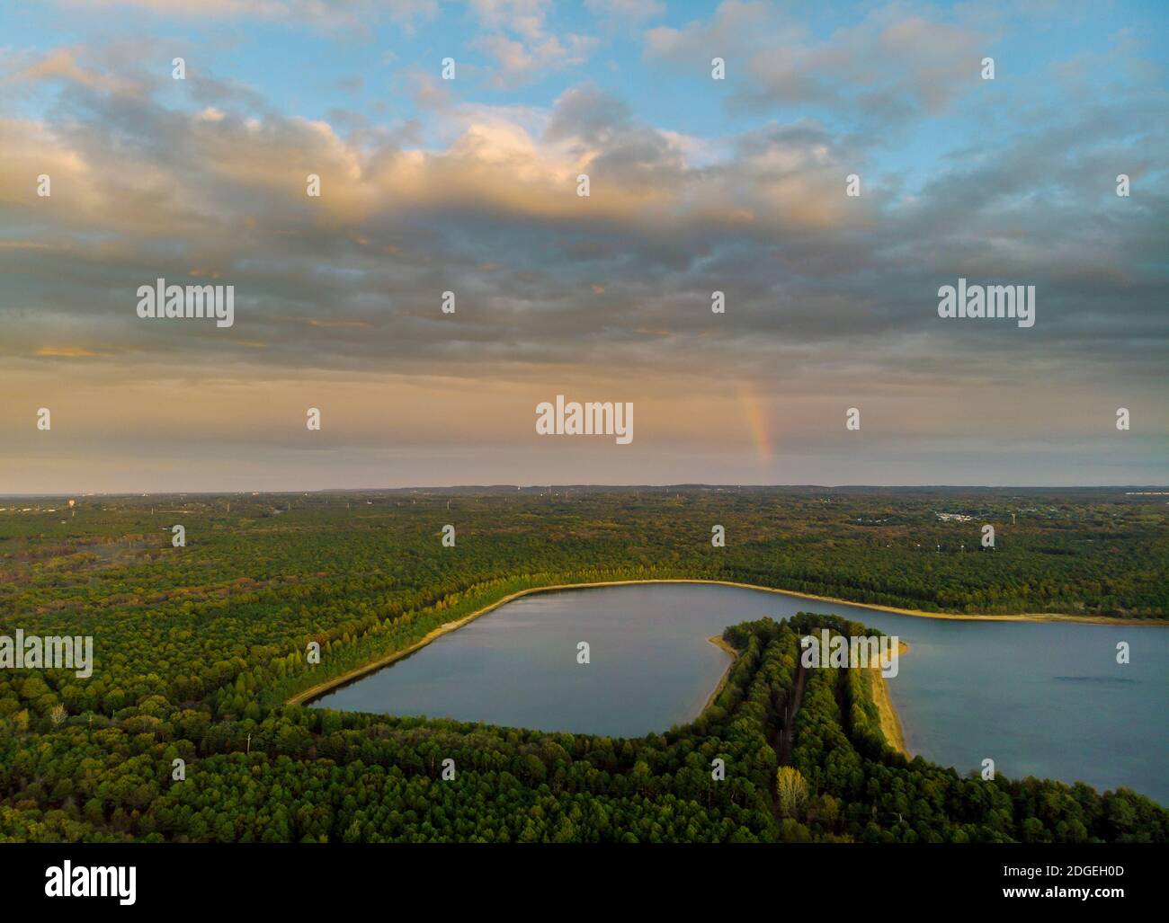 Arcobaleno nella bella scena del tramonto su un lago con cielo della foresta Foto Stock