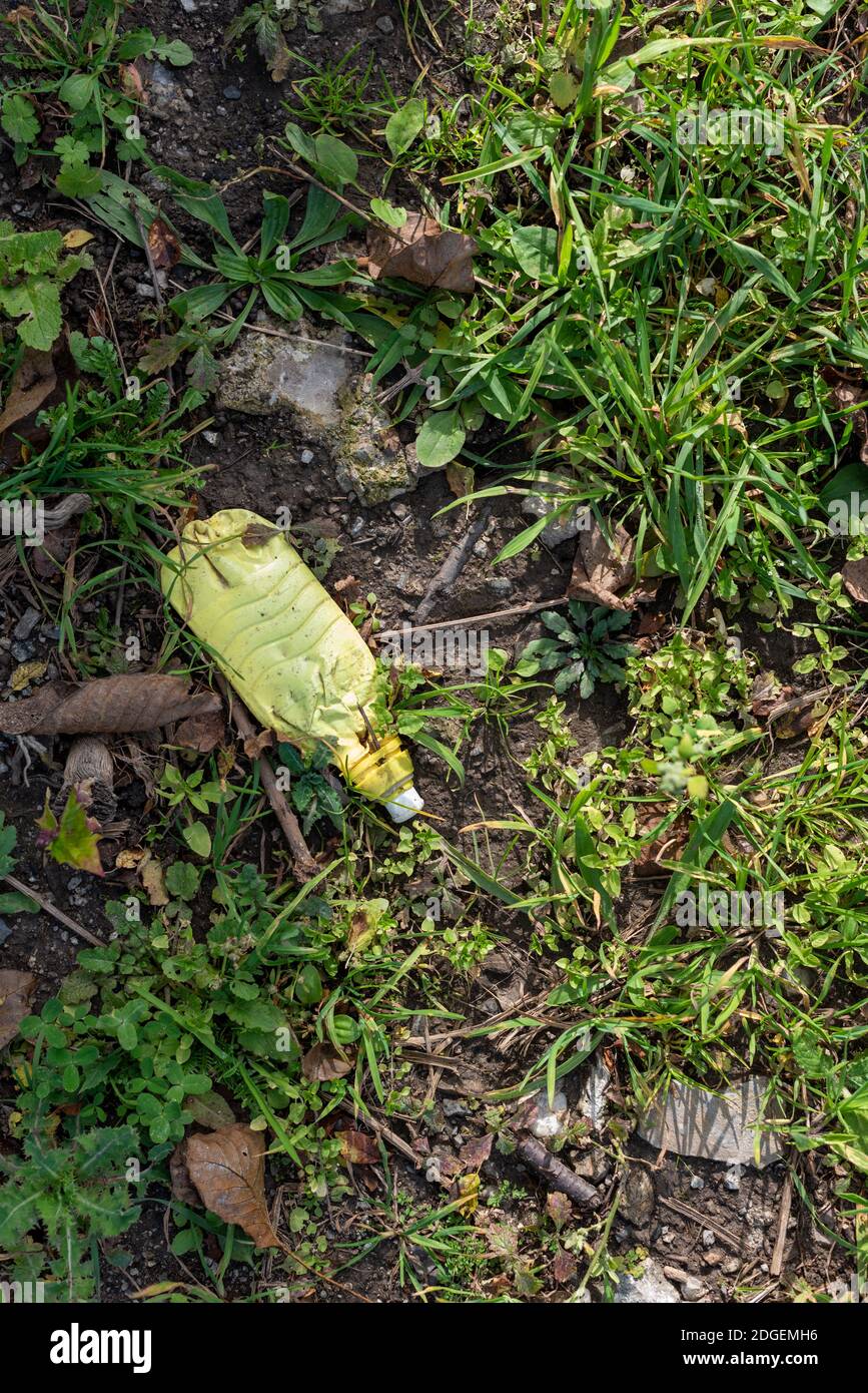 Vecchia plastica invecchiata in erba foresta sporco inquinamento questione ambientale conversazione Foto Stock