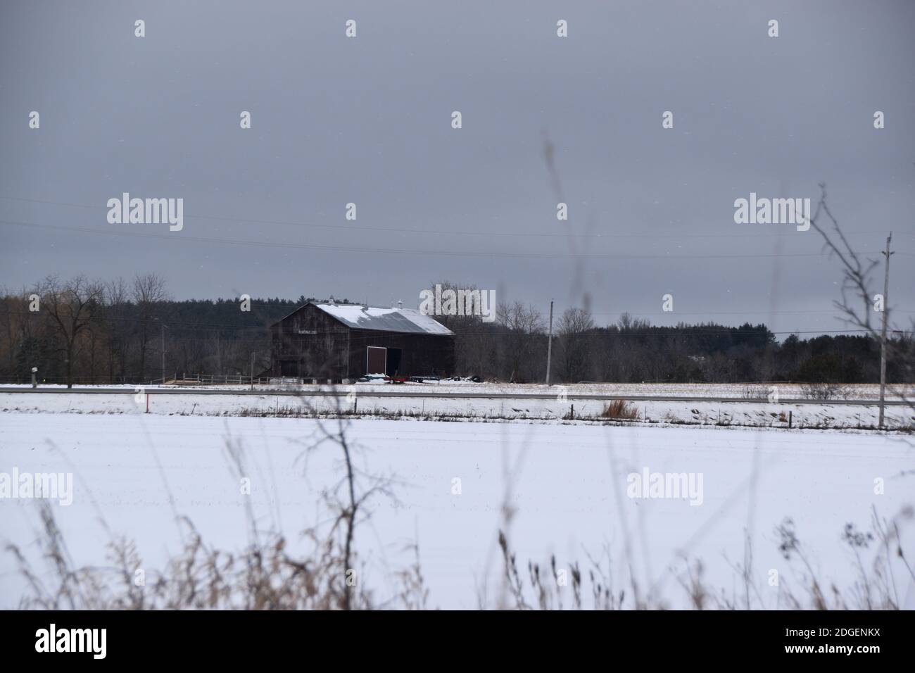 Un fienile nevoso nel mezzo di un campo di neve Foto Stock