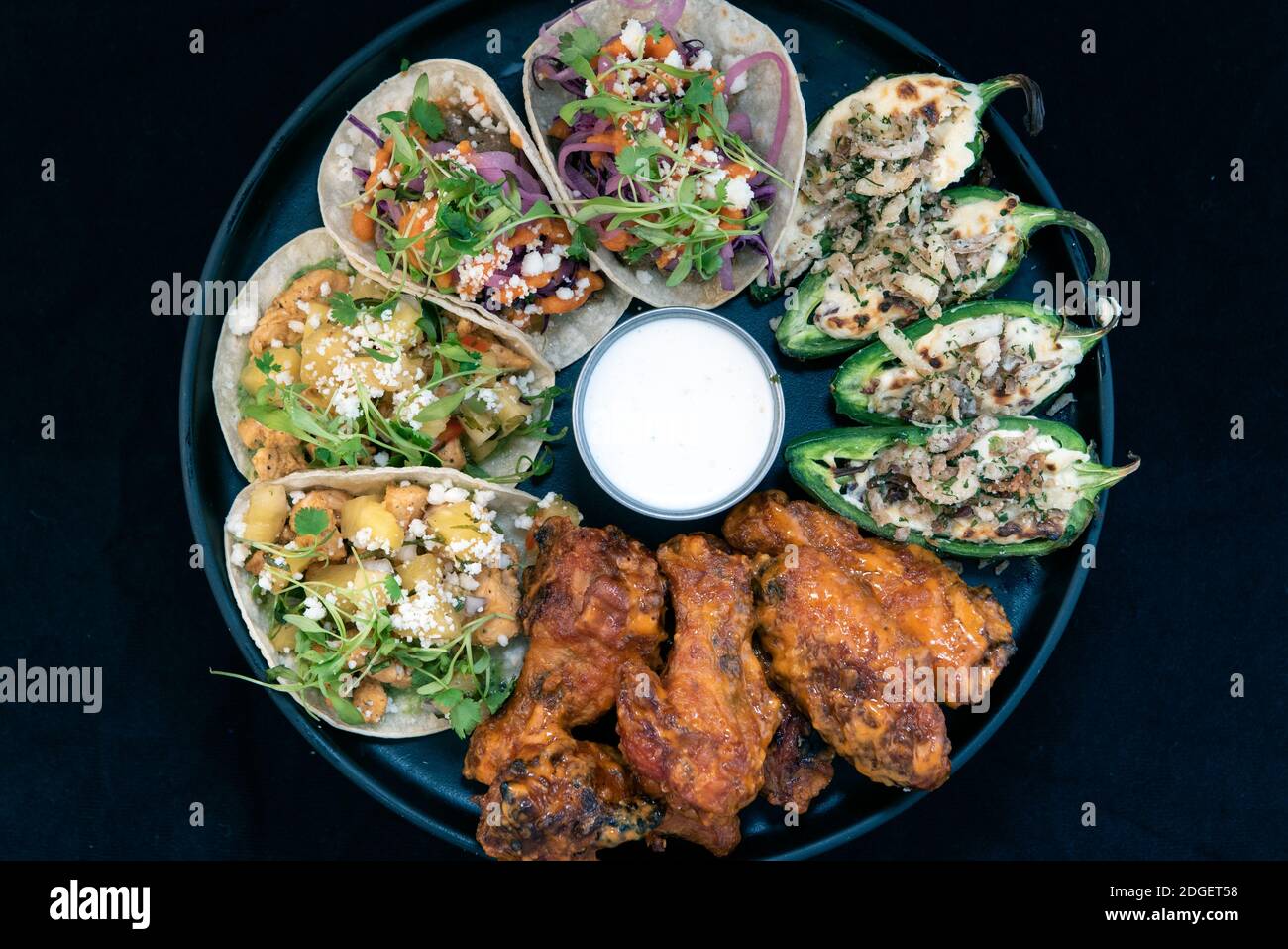 La vista dall'alto del delizioso piatto assaggiatore di antipasti con tacos di pollo e bistecca, poppers e ali di bufalo fa crescere l'acqua della bocca e lo stomaco Foto Stock