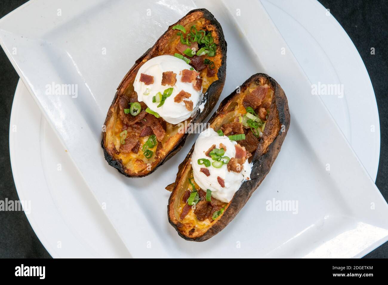 Vista dall'alto di un delizioso piatto di antipasti con bucce di patate al forno con panna acida, formaggio e erba cipollina che fa crescere l'acqua della bocca e lo stomaco. Foto Stock