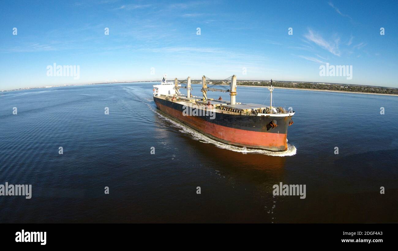 Una nave di carico si direa verso l'Oceano aperto fuori Un porto Foto Stock