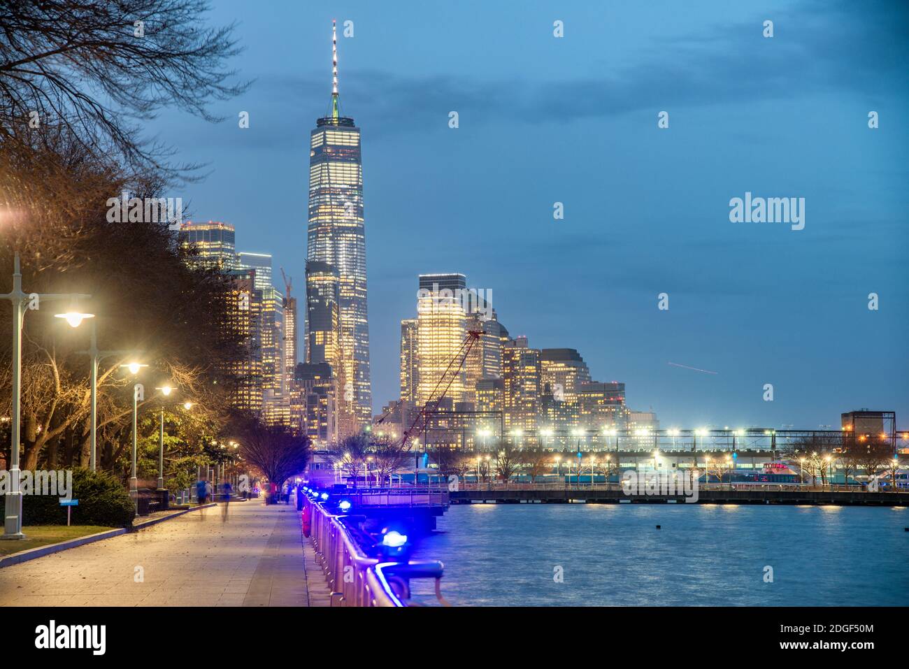 Skyline notturno del centro di Manhattan dall'Hudson River Park. Grattacieli luci e molo della città Foto Stock