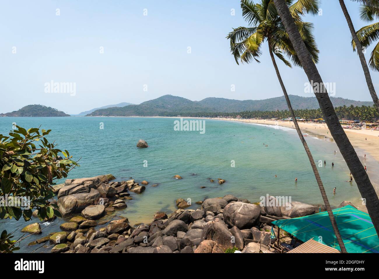 Vista delle rocce costiere, palme e montagne all'orizzonte vicino alla spiaggia di Palolem a Goa, India Foto Stock