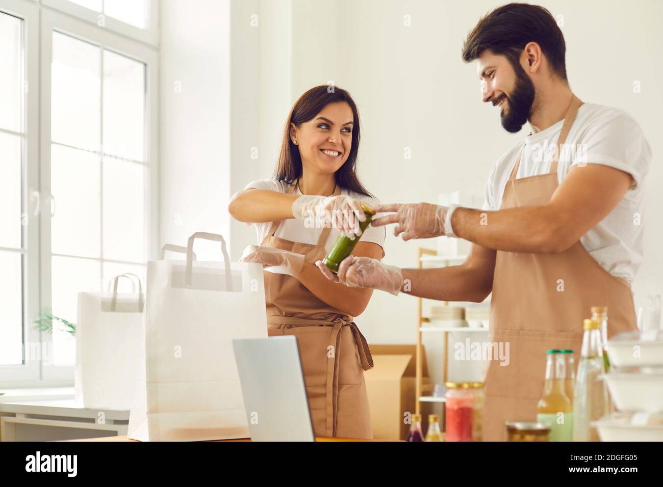 Addetti alla consegna di alimenti che imballano cibo sano takeout scatola e bevande a sacchetti di carta per la consegna Foto Stock