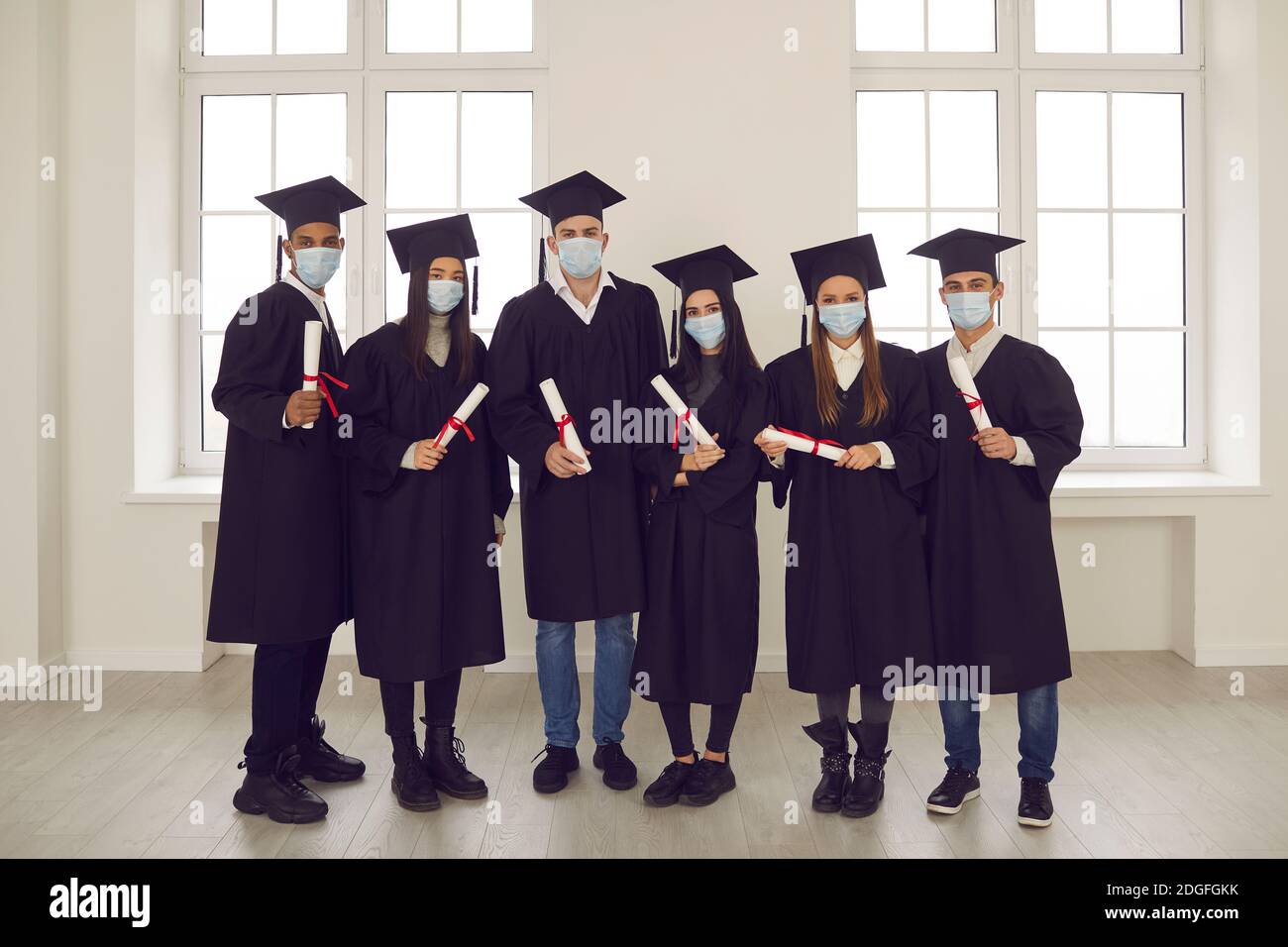 Ritratto di studenti di successo con diplomi in mano e maschere mediche sul viso. Foto Stock