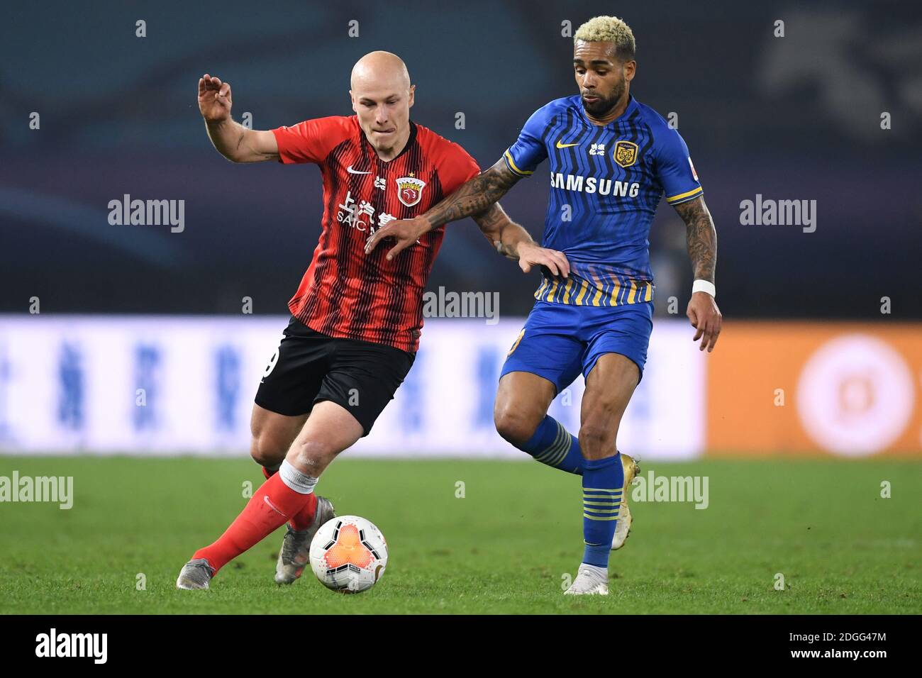 Il calciatore professionista australiano Aaron Mooy di Shanghai SIGG F.C., a sinistra, lotta per la palla contro il calciatore brasiliano Alex Teixeira Foto Stock