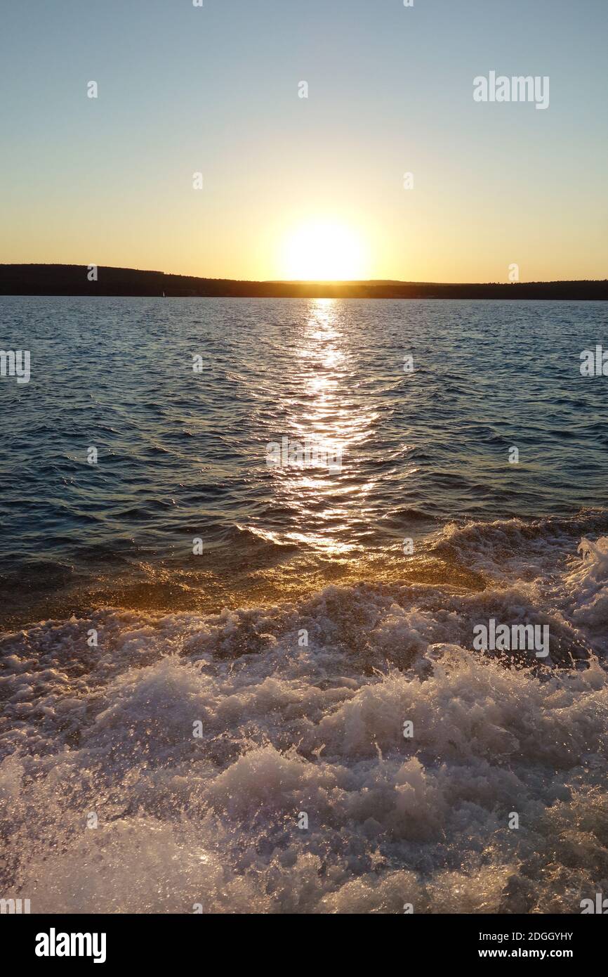 Tramonto sul lago con le onde della barca Foto Stock