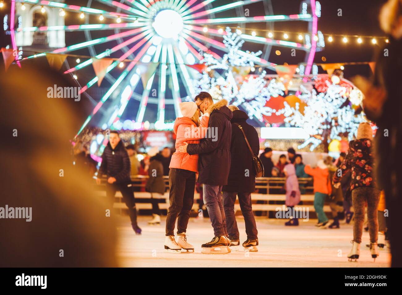 Coppia abbracciando San Valentino. Giovane coppia romantica divertirsi all'aperto in inverno. San Valentino presso la pista di pattinaggio della città. Foto Stock