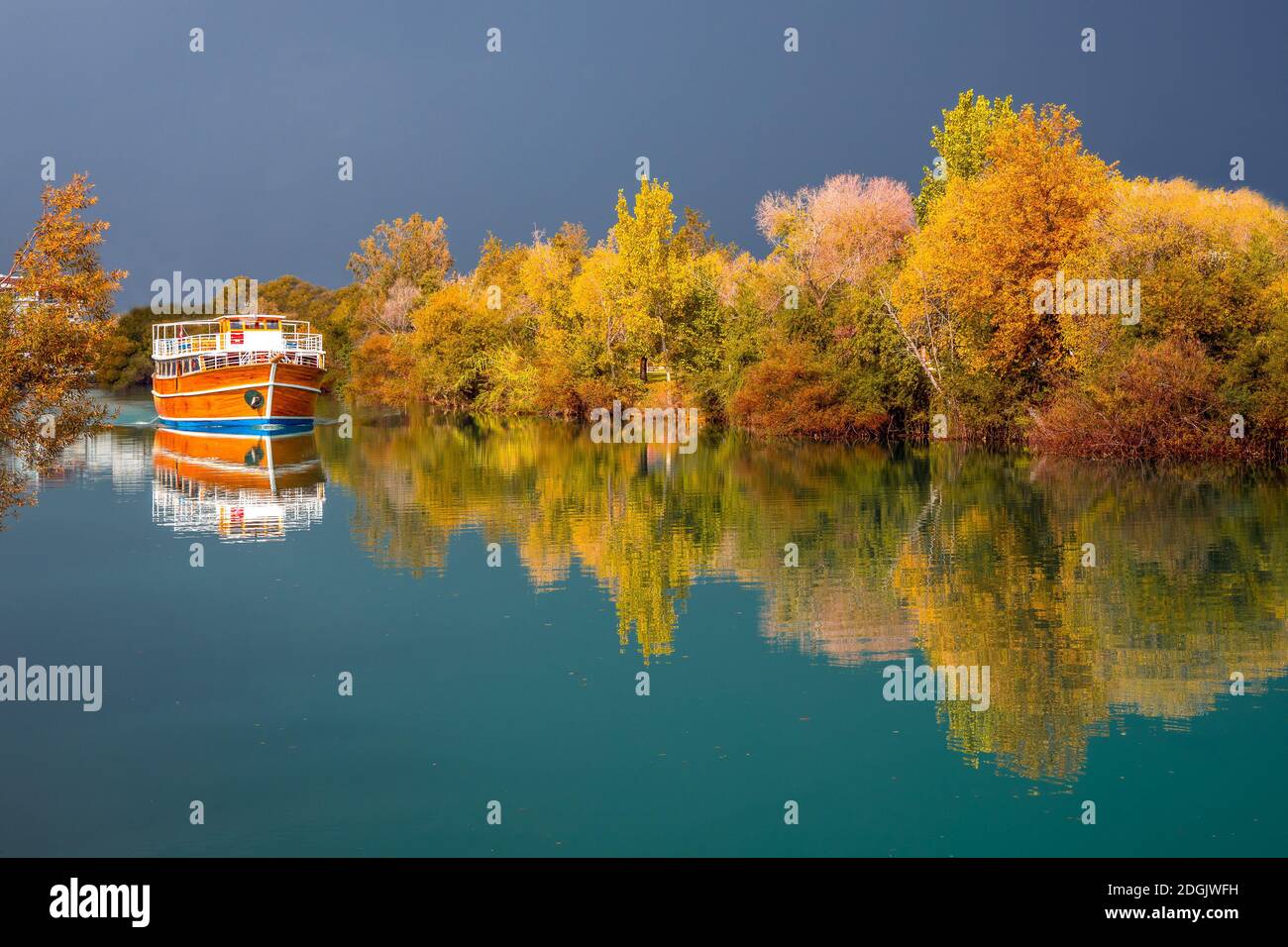 Paesaggio autunnale, riflessione di alberi e barca in acqua al fiume Manavgat Antalya Foto Stock