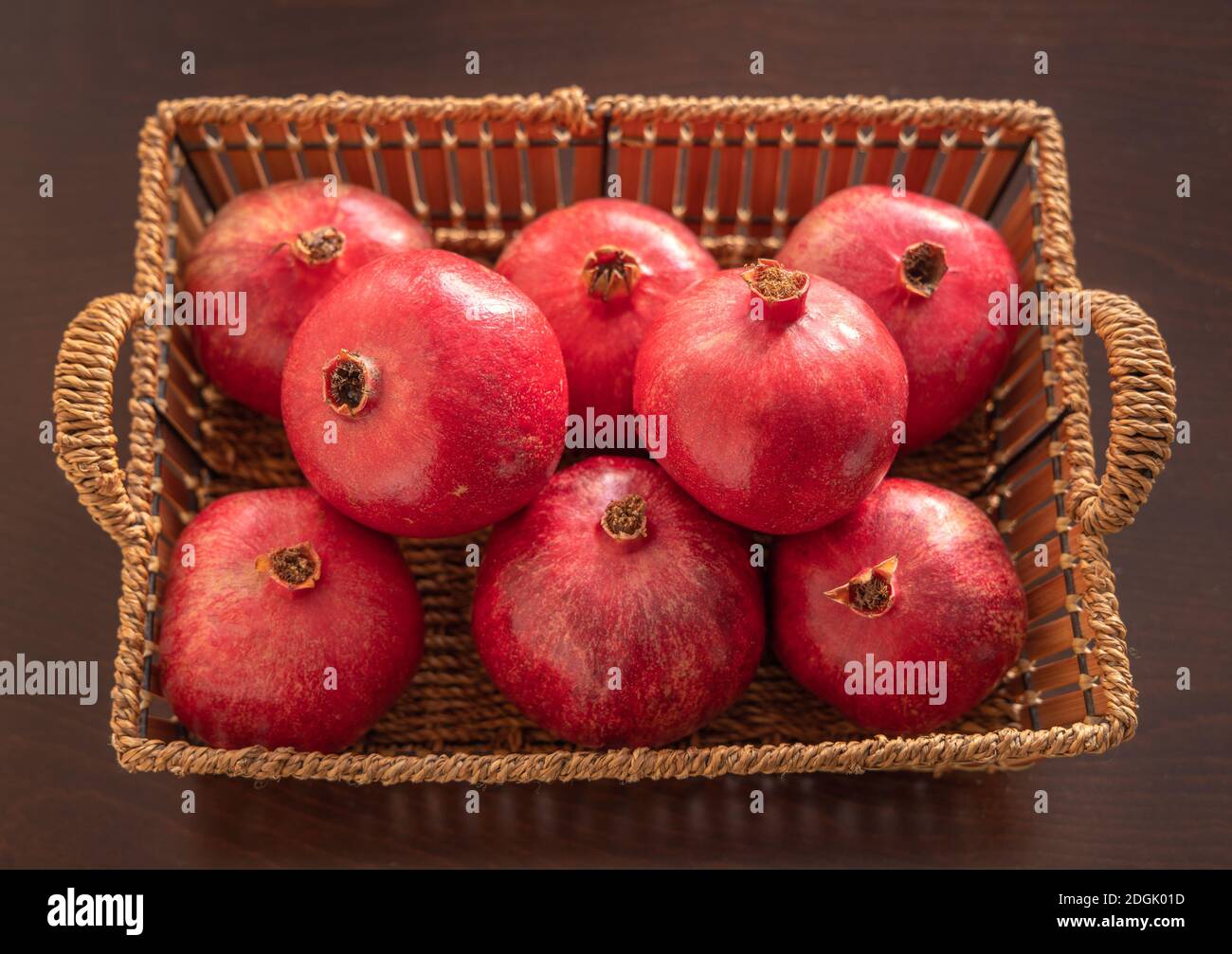 Melograni freschi di frutta rossa in un cestino. Sfondo di legno. Foto Stock
