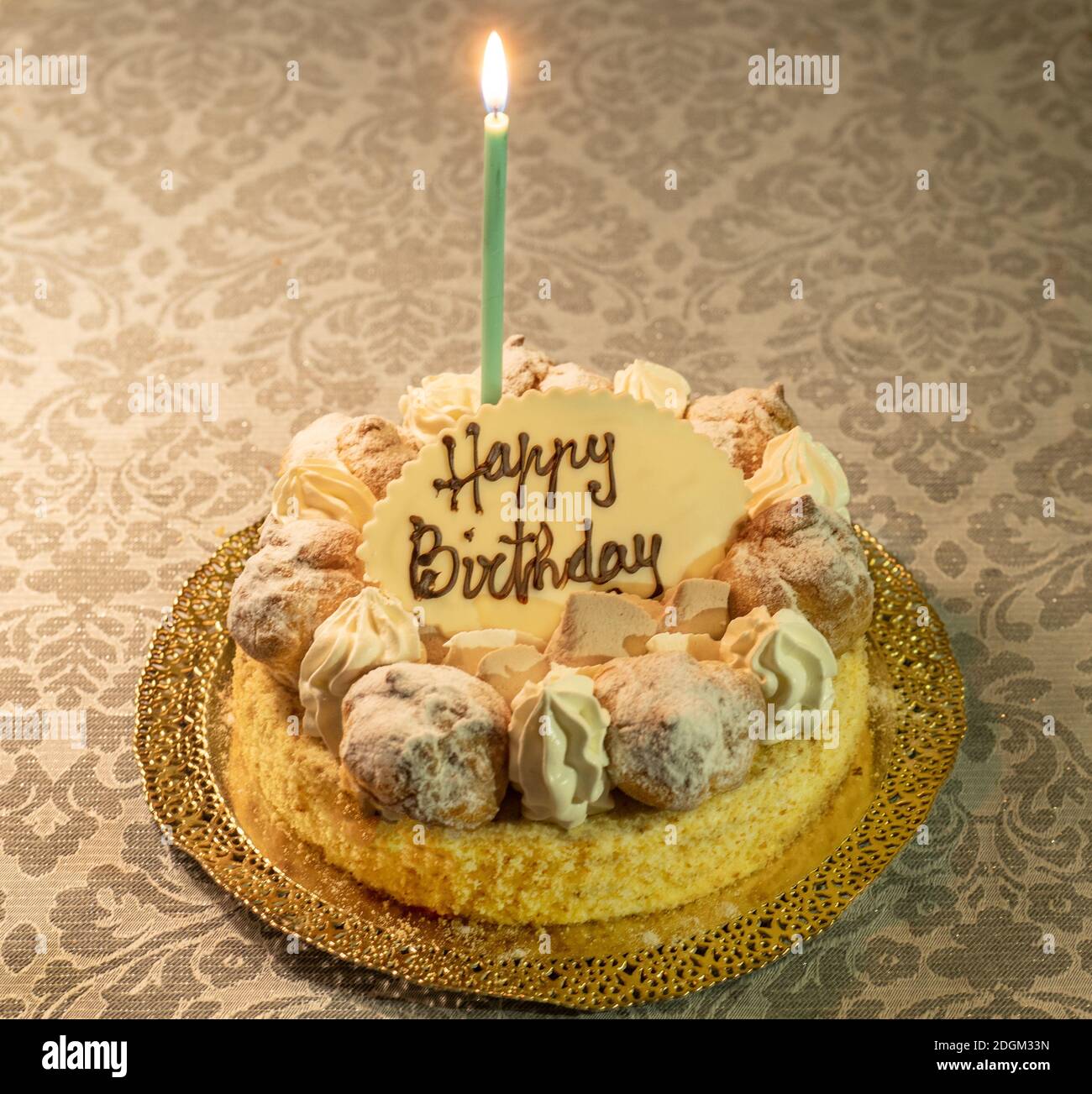Torta Saint Honore con candela e piatto di cioccolato con felice Scrittura di compleanno Foto Stock