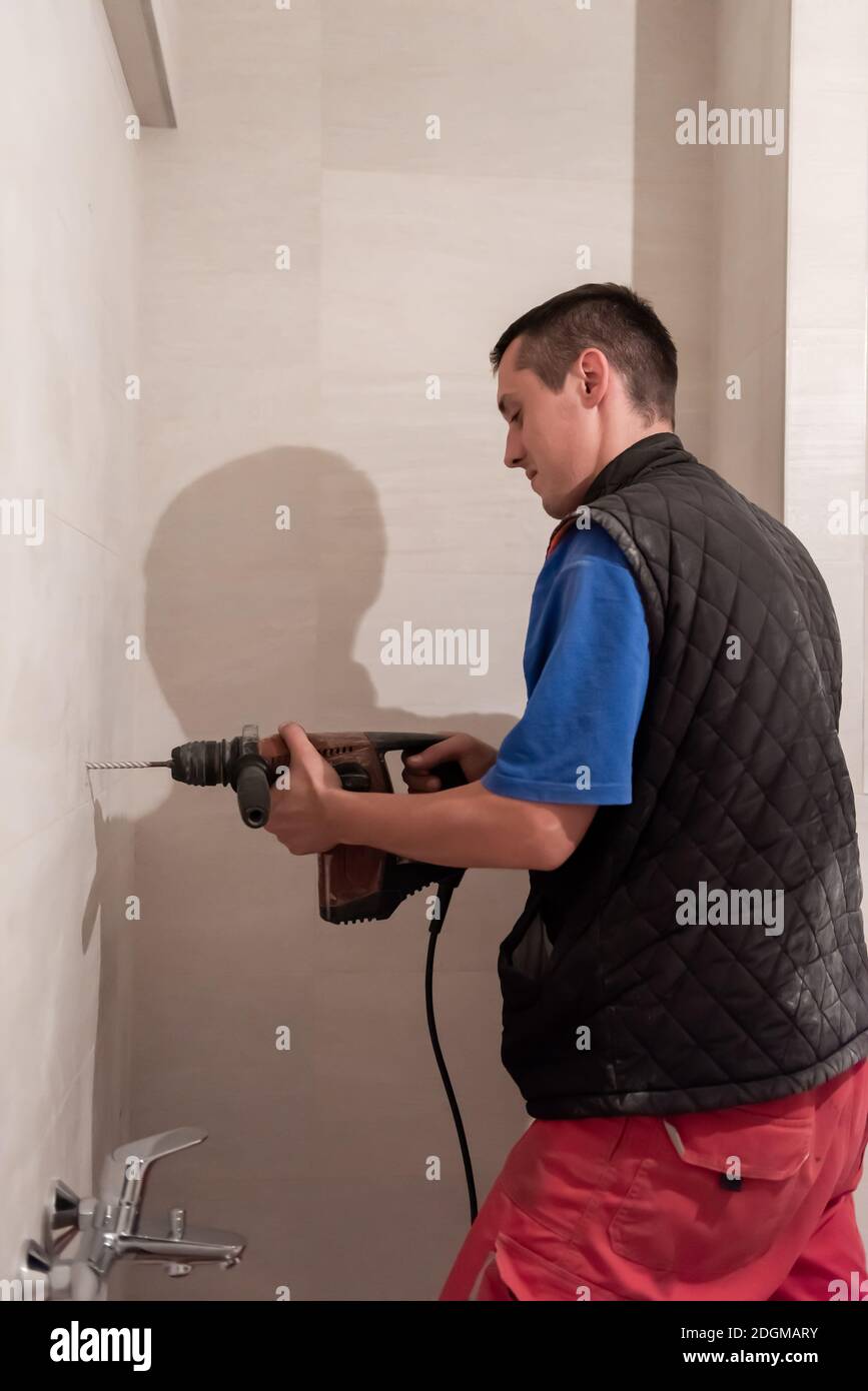 Lavoro di costruzione che perfora i fori nel bagno Foto Stock