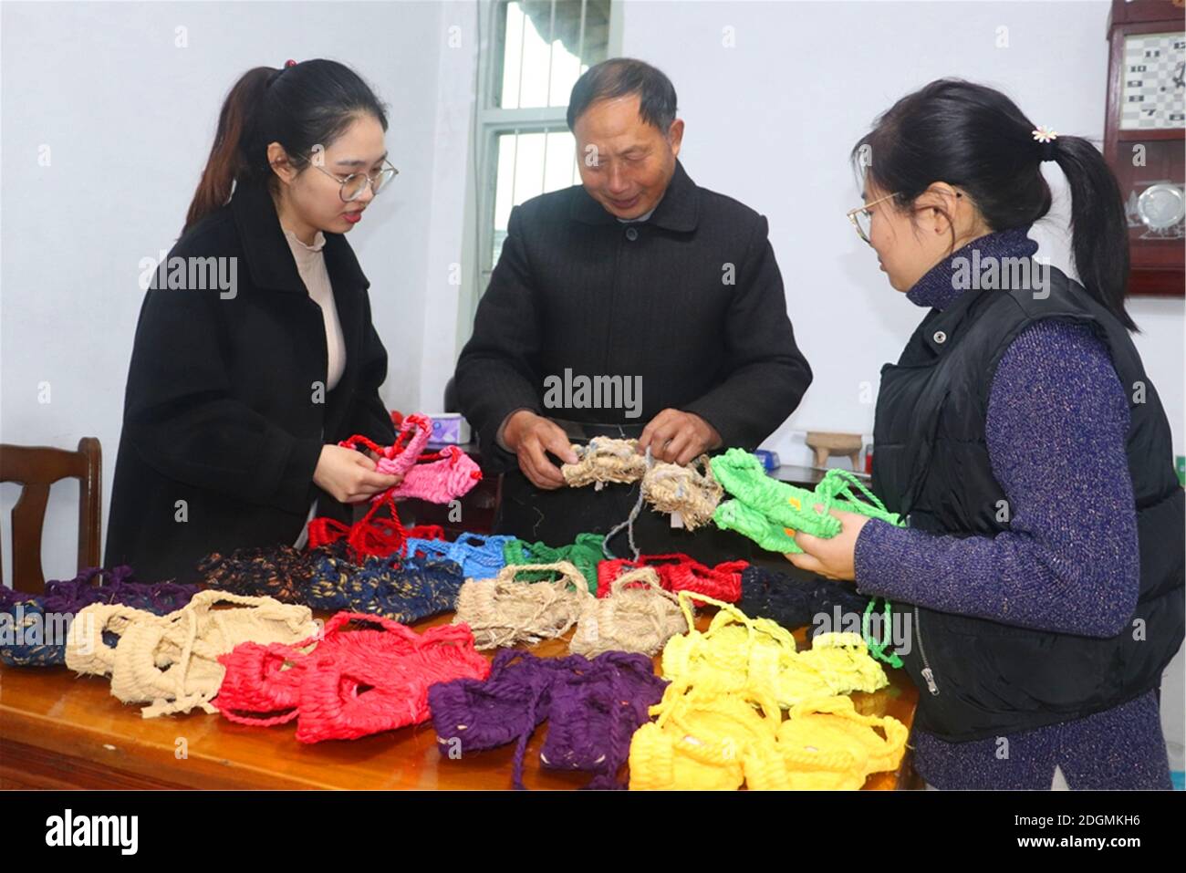 Un uomo di settantasei anni tesse strisce di paglia e stoffa in squisite scarpe di paglia in stili diversi nella città di Zhenjiang, il provin Jiangsu della Cina orientale Foto Stock