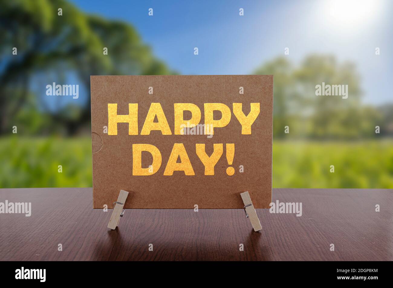 Testo del giorno felice sulla carta sul tavolo con sfondo verde soleggiato del parco. Foto Stock