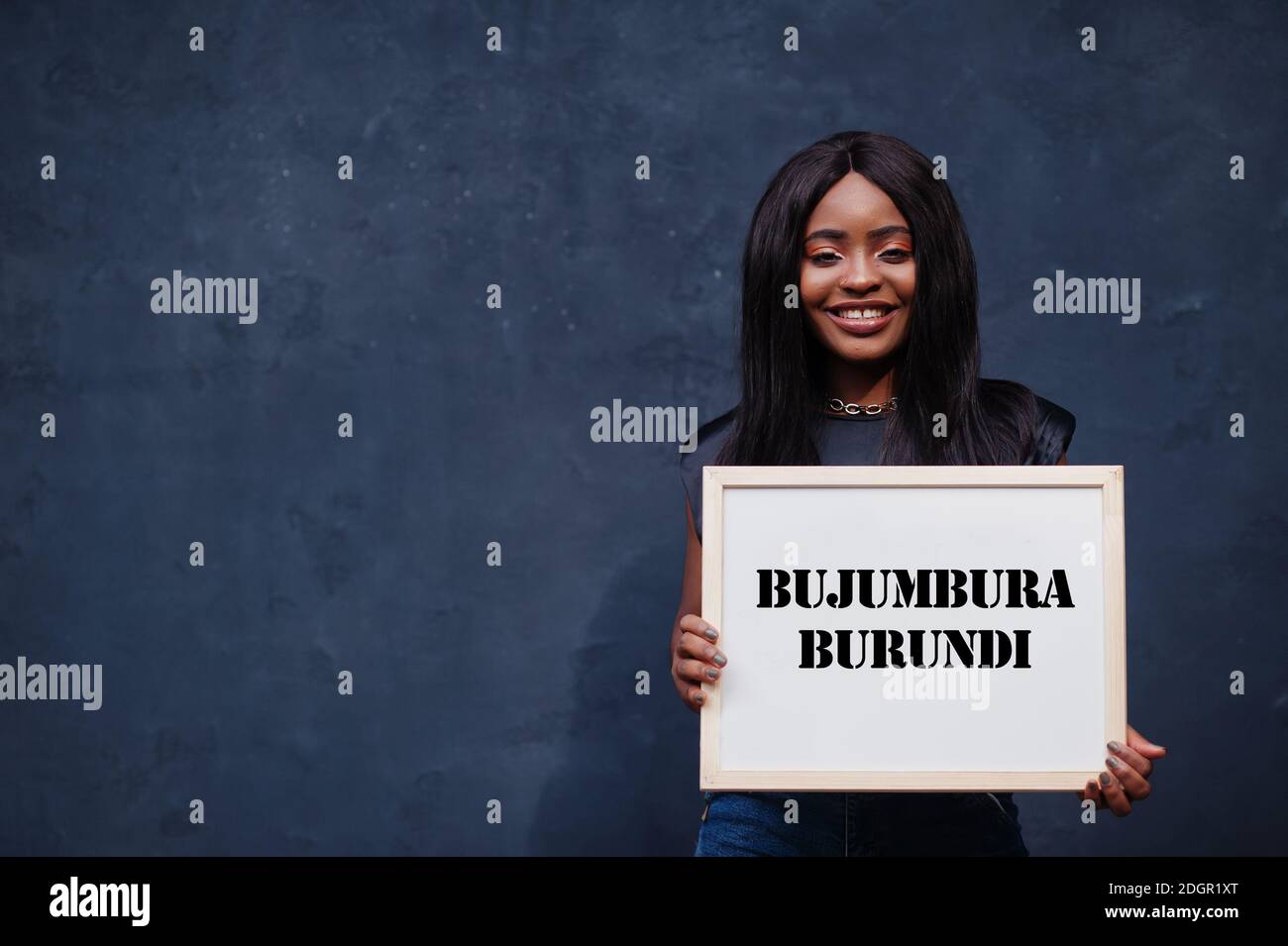 Donna africana tiene il bordo bianco con l'iscrizione Bujumbura Burundi. La città più popolosa in Africa concetto. Foto Stock