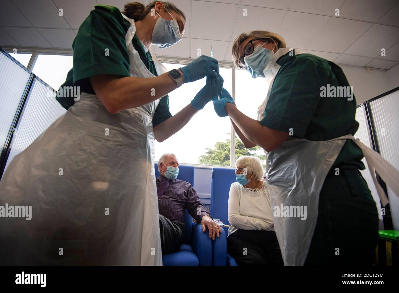 Gli infermieri controllano la dose del vaccino Pfizer/BioNTech covid-19 prima che il marito e la moglie Vic e Penny Griffiths ricevano l'iniezione al Basildon University Hospital, a Basildon, Essex, come il più grande programma di immunizzazione mai realizzato nella storia del Regno Unito continua. Foto Stock