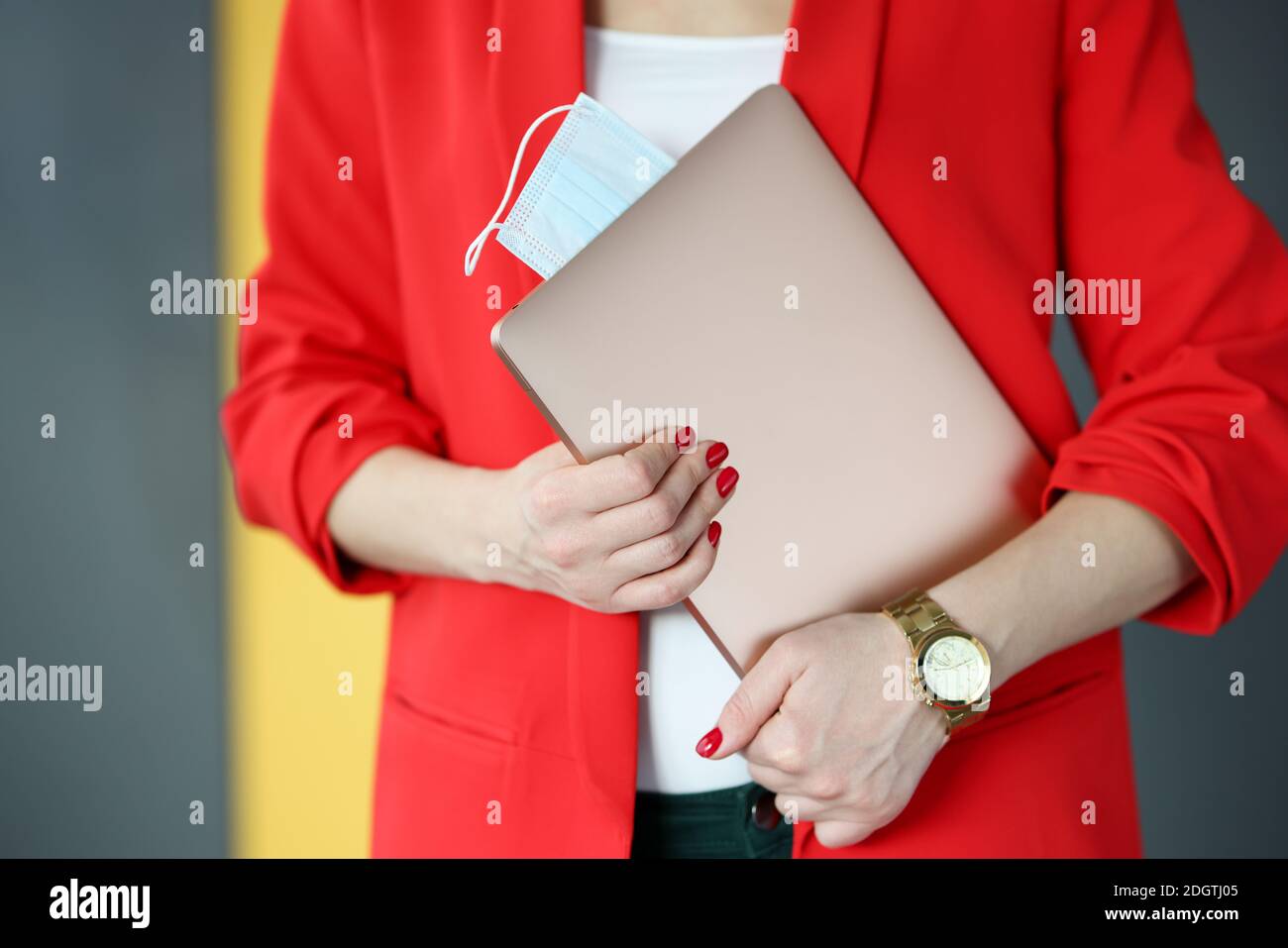 Donna in tuta rossa che tiene un computer portatile con mascherine di protezione primo piano Foto Stock