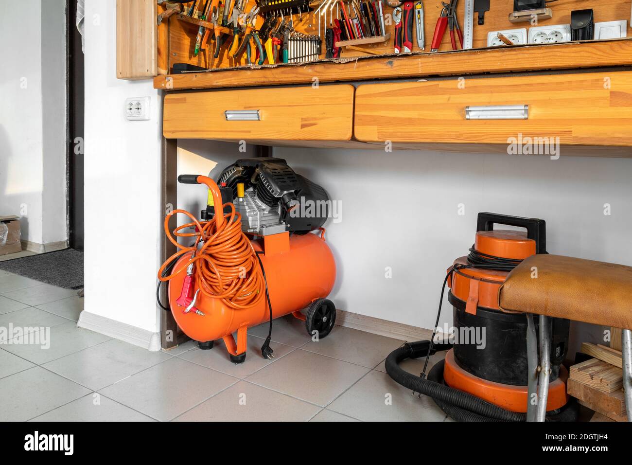 Piccolo compressore d'aria industriale portatile arancione con tubo  flessibile a spirale e pistola pneumatica e aspirapolvere nel garage di  magazzino domestico sotto legno Foto stock - Alamy