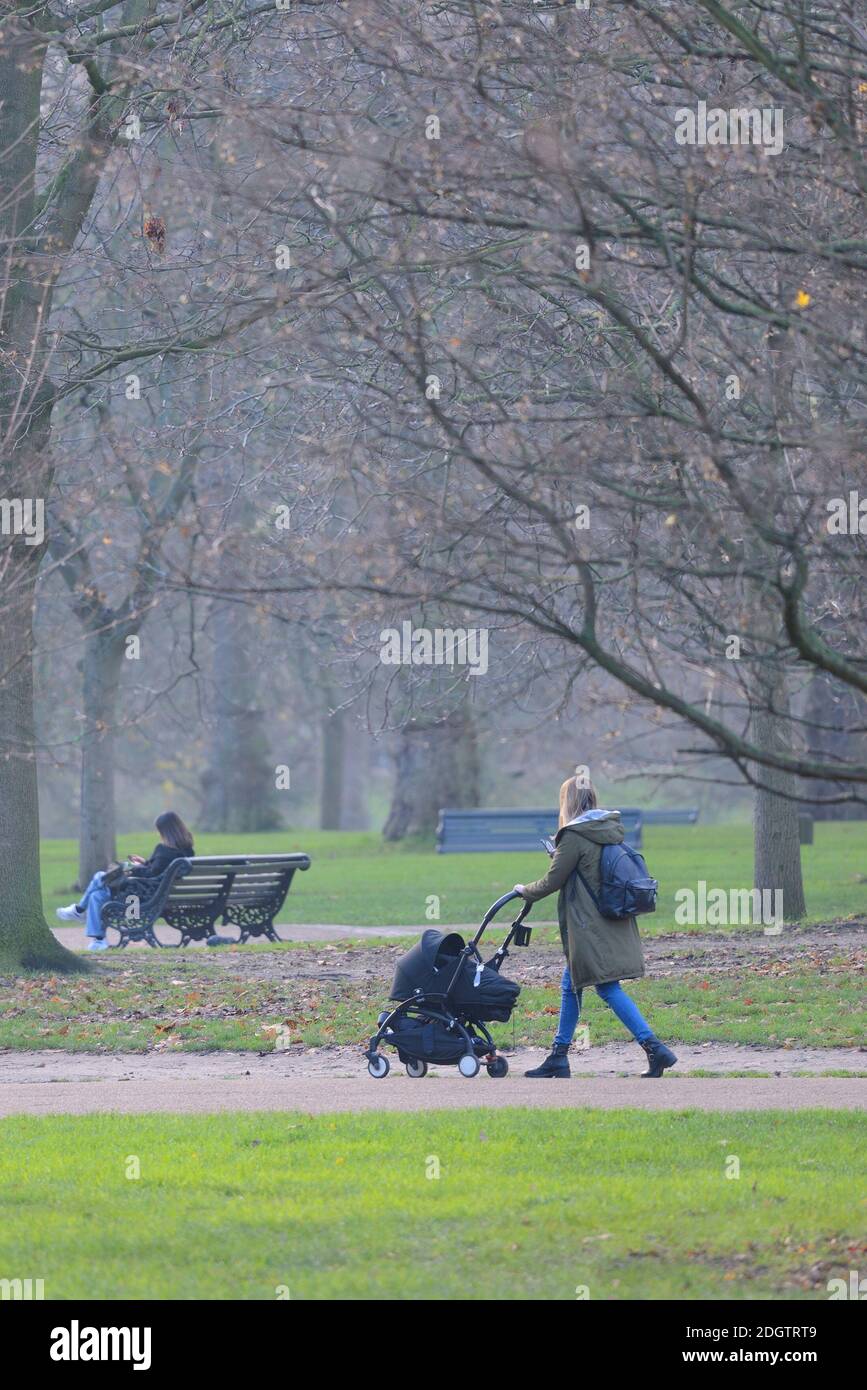 Londra, Inghilterra, Regno Unito. Giovane madre che cammina in una giornata di nebbia a Green Park, dicembre 2020 Foto Stock