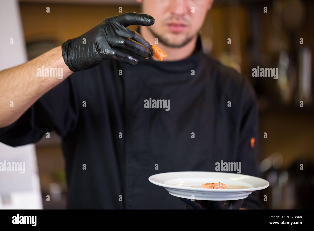 La cucina a tema è la professione di cucina. Ritratto di uomo caucasico in cucina ristorante preparazione di filetti di pesce rosso carne di salmone i Foto Stock