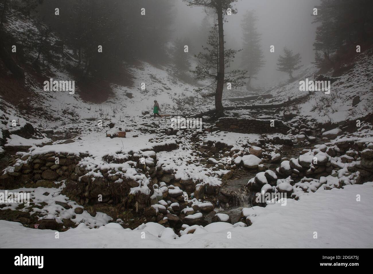 Srinagar, Kashmir. 9 Dic 2020. Una donna cammina in mezzo alla nebbia dopo una fresca nevicata in un villaggio nel quartiere di Baramulla vicino alla città di Srinagar, la capitale estiva di Kashmir, 9 dicembre 2020. Credit: Javed Dar/Xinhua/Alamy Live News Foto Stock