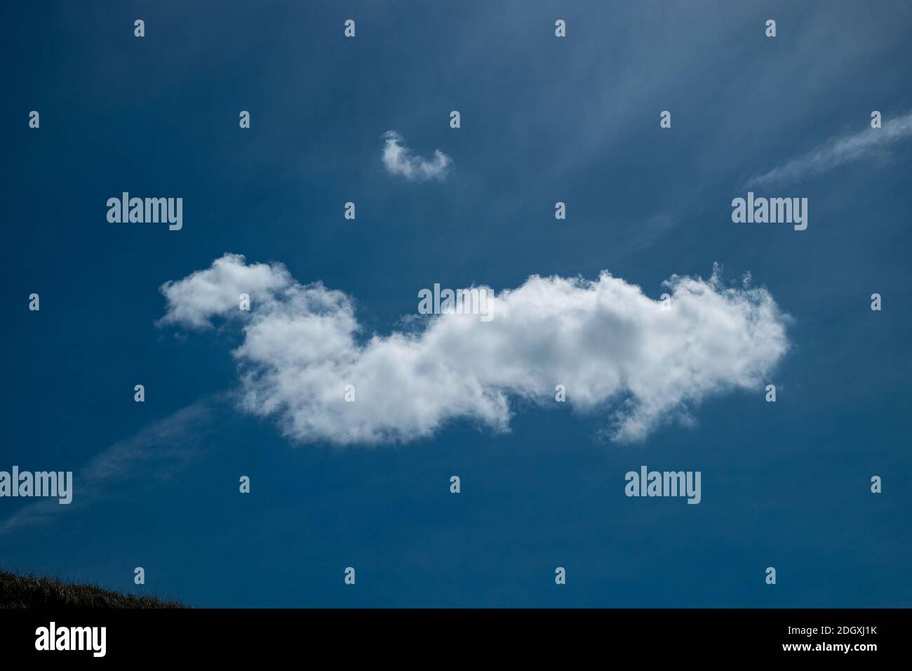 Definizione di una singola nuvola bianca su un cielo blu profondo Foto Stock