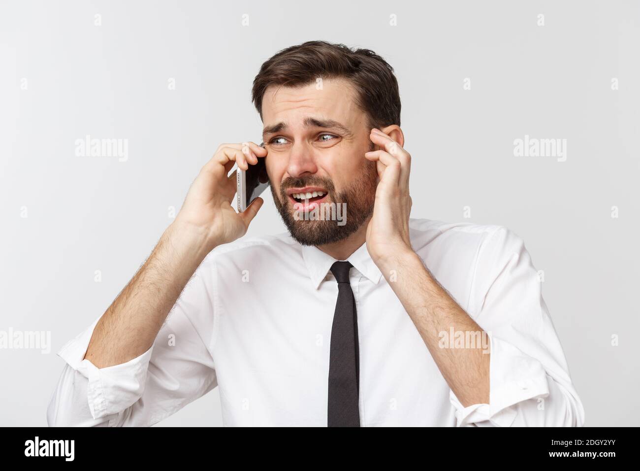 Uomo d'affari arrabbiato e serio che parla al telefono su sfondo grigio Foto Stock