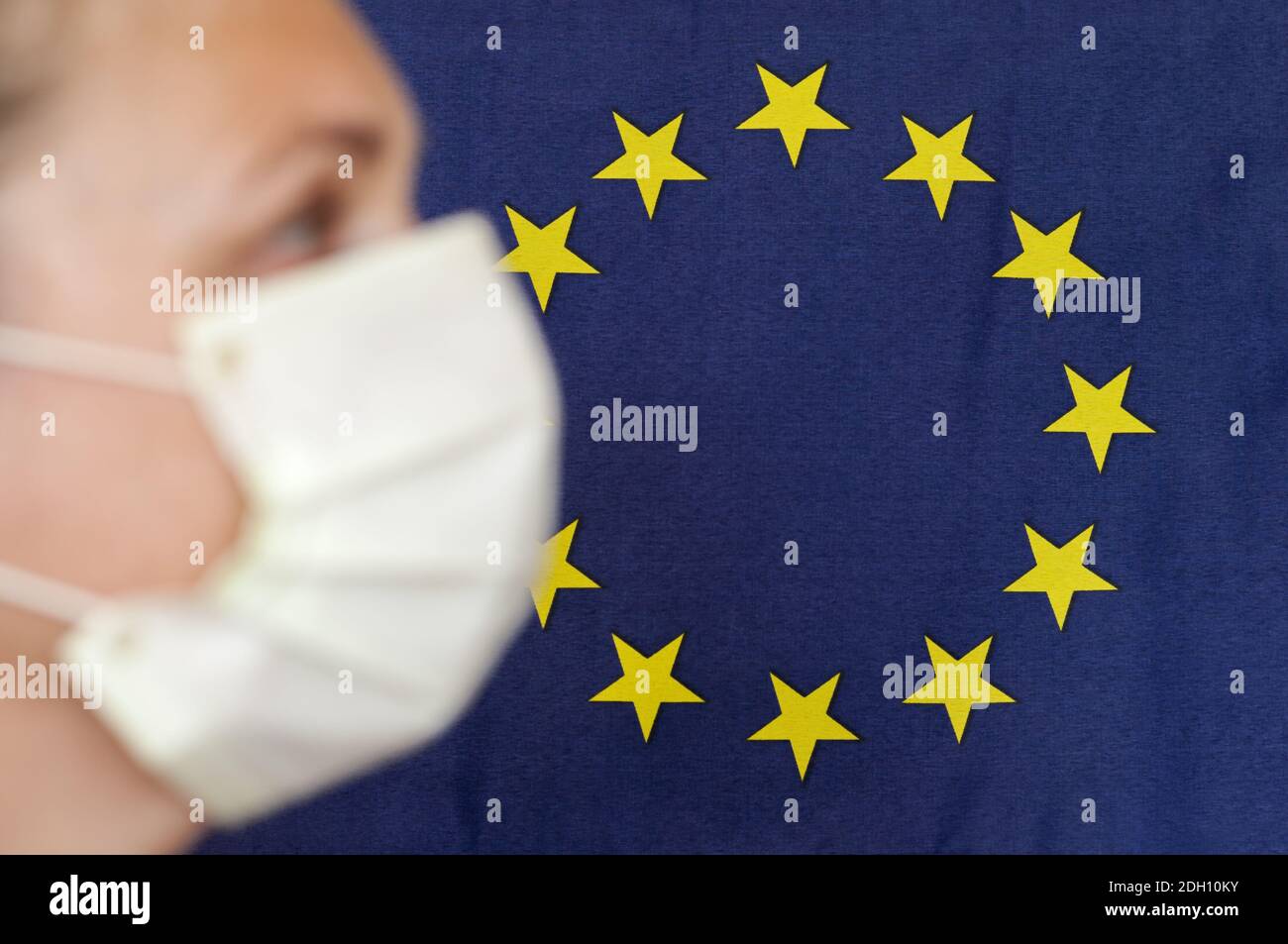 Donna con maschera di fronte alla bandiera dell'Unione europea in profilo. Foto Stock