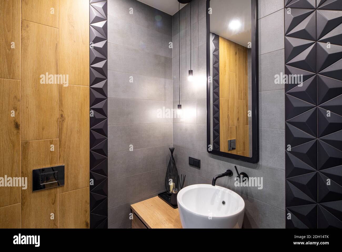 Interni contemporanei del bagno. Lavello bianco. Specchio a parete. Design in legno. Tessera grigia e nera. Foto Stock