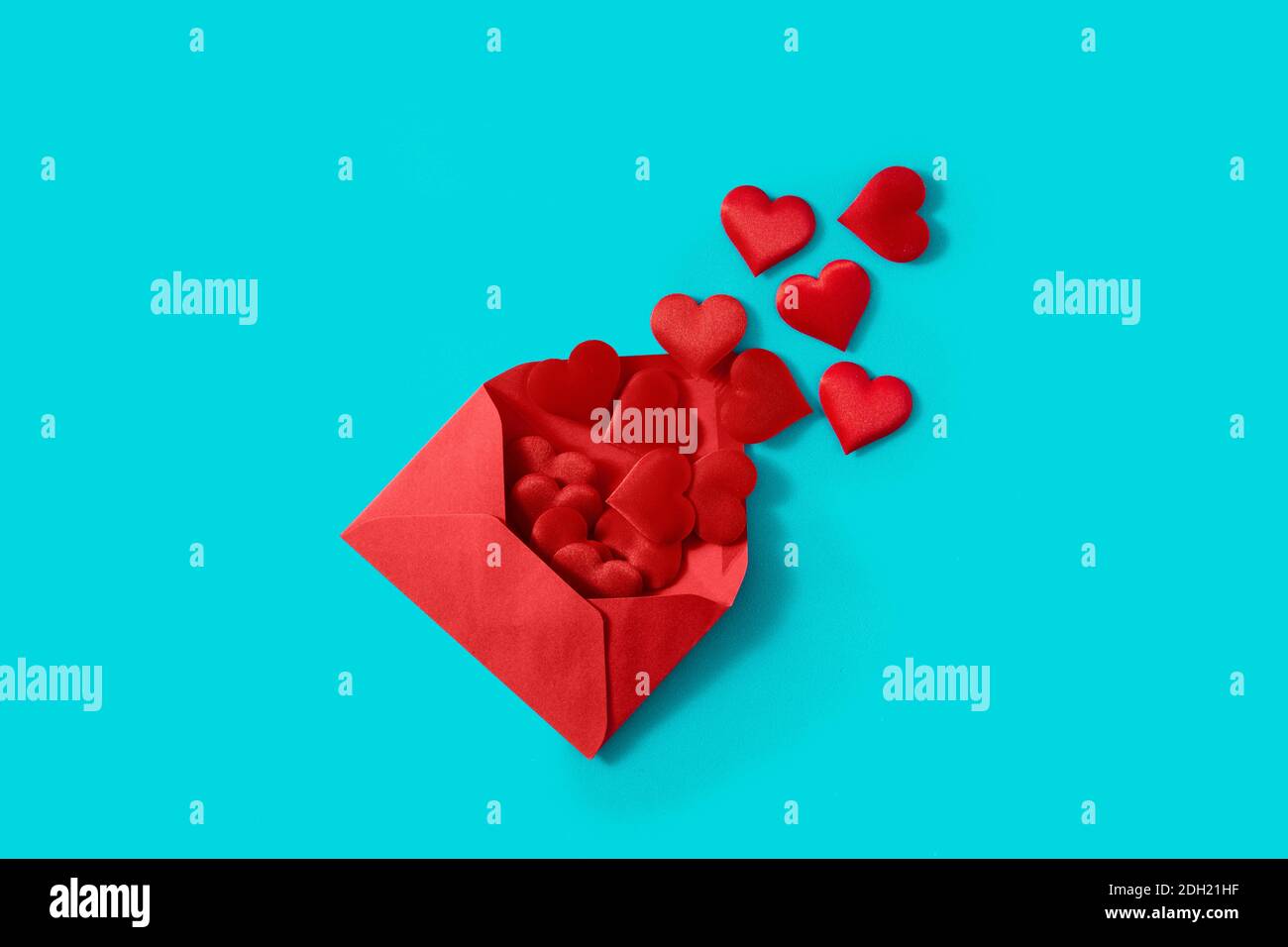 Cuori che escono da una busta rossa su sfondo blu Foto Stock