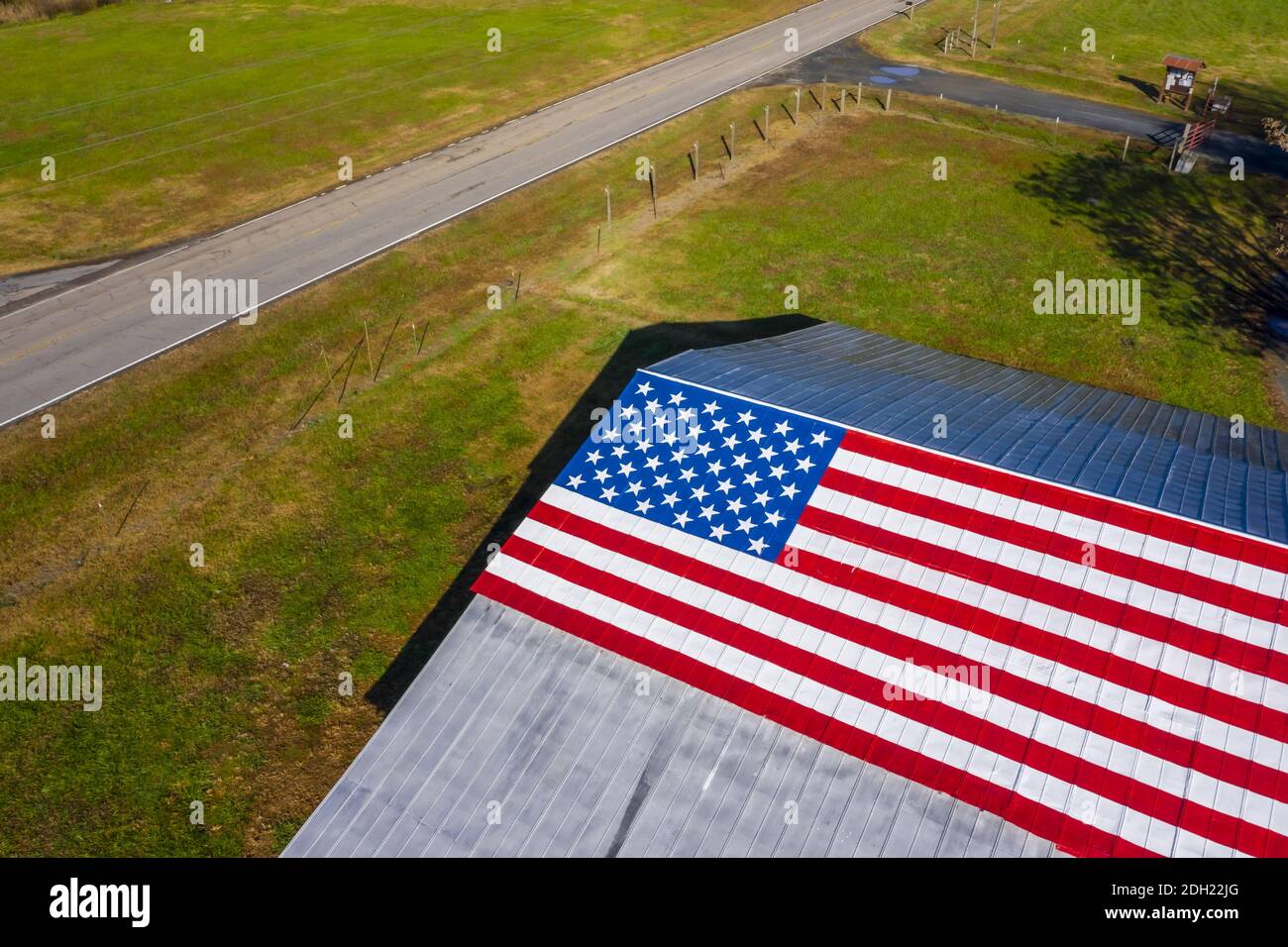 Una bandiera americana dipinta su un granaio vicino AD UN paese Strada Foto Stock