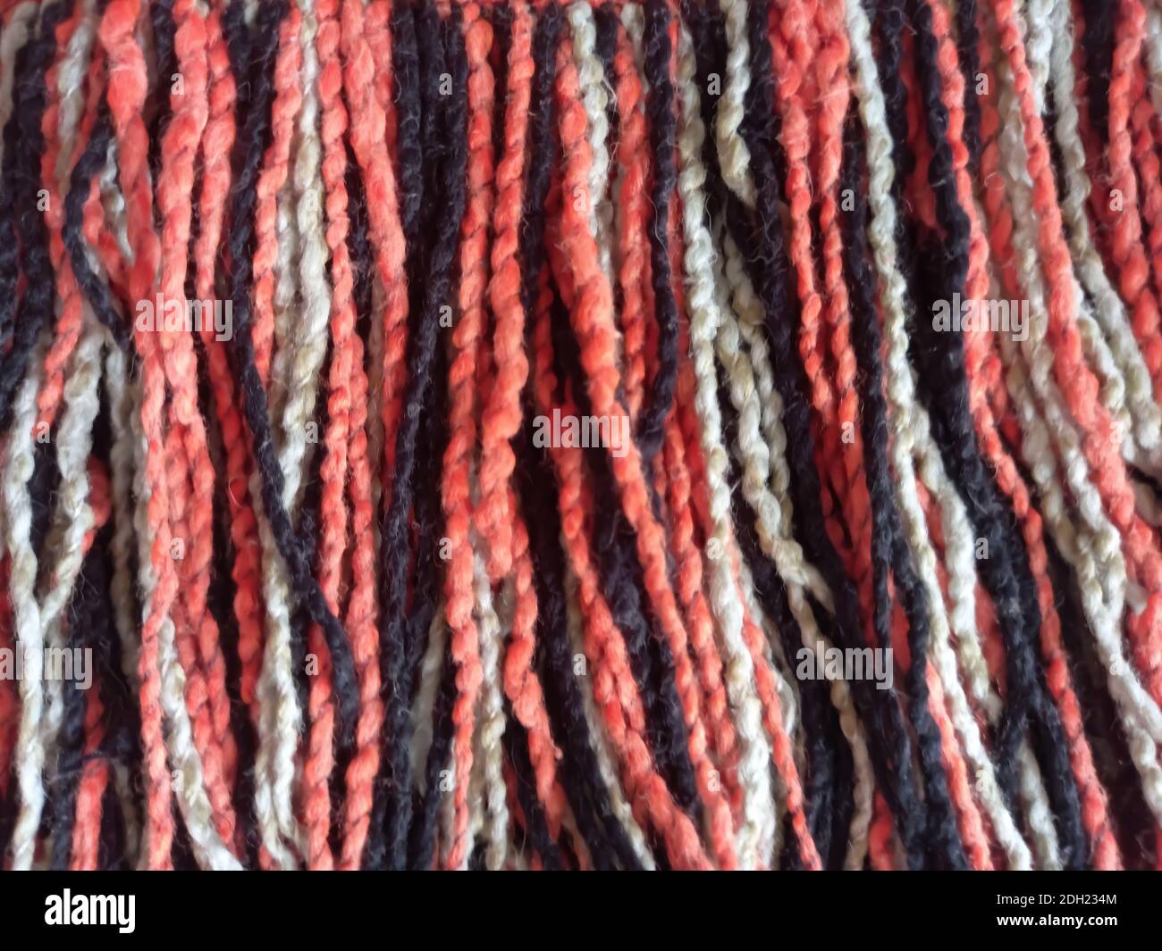 Uno sfondo o una trama di frange di lana di diversi colori (nero, rosso, bianco, arancione) Foto Stock