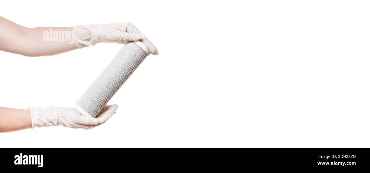filtro a cartuccia per la purificazione dell'acqua potabile, rete di carbone per dimostrare la tenuta in mani in guanti sterili isolati su fondo bianco banner con Foto Stock