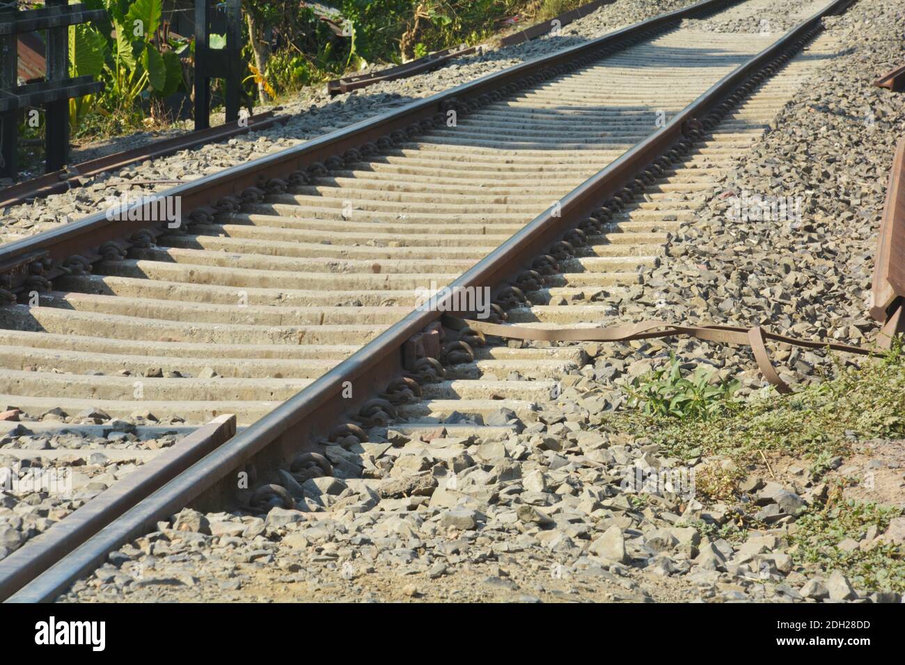 Primo piano di linee ferroviarie, binari ferroviari, ferrovia di Indian Railway con ringhiere ferroviarie, pietre su una ferrovia che attraversa una strada, focalizzazione selettiva Foto Stock