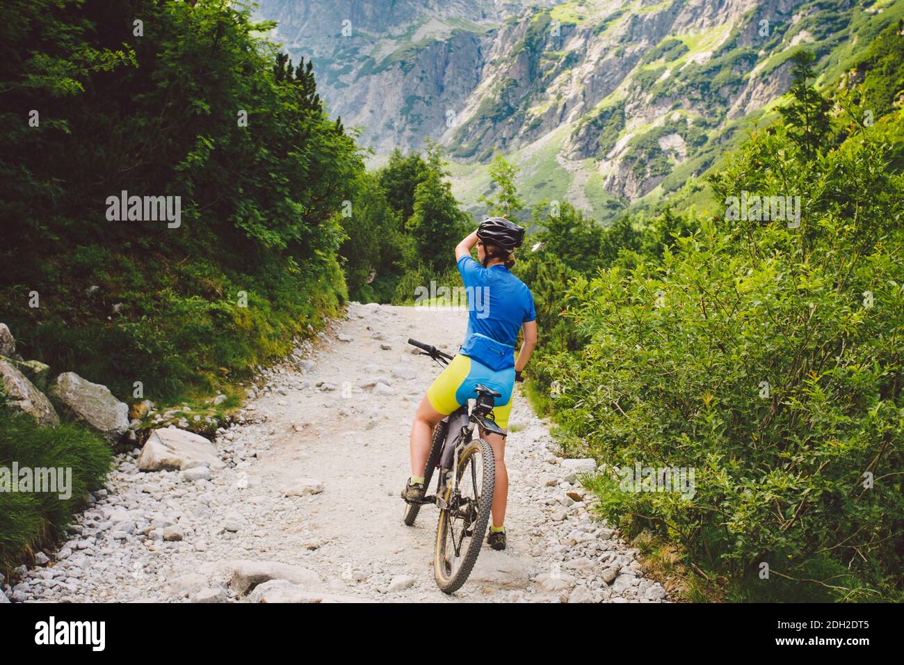 Ragazza in bicicletta viaggia in Slovacchia. Casco nero, camicia blu, montagne, alti Tatra, Foto Stock