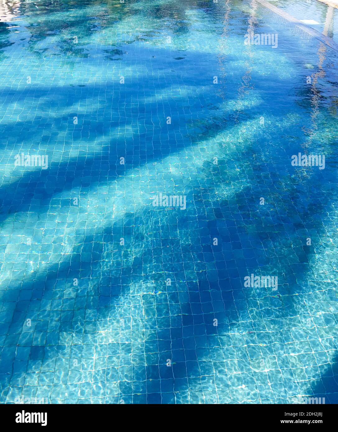 Piscina d'acqua con increspature e rifrazioni su piastrelle blu Foto Stock