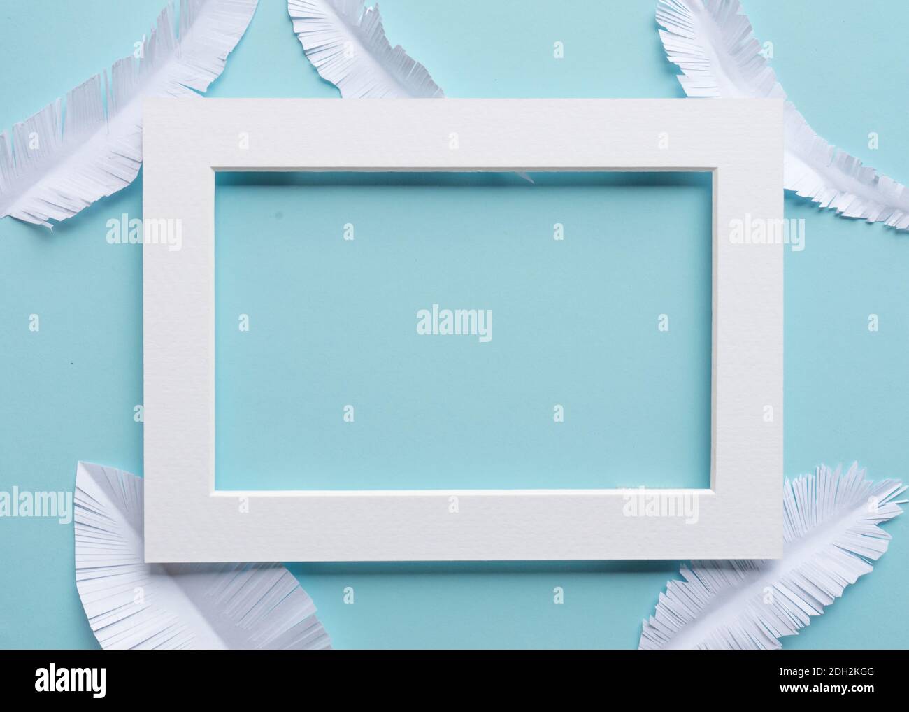 cornice bianca con piume di carta bianca su sfondo blu del bambino con spazio per la copia Foto Stock