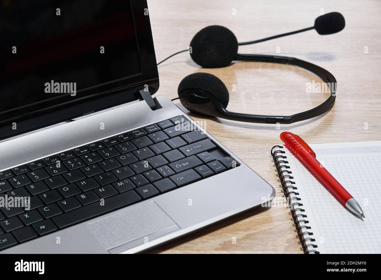 laptop, cuffie con microfono, notebook e penna sul tavolo da primo piano Foto Stock