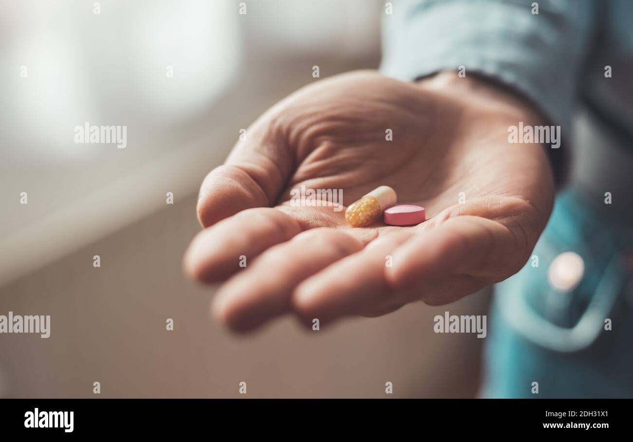Concetto di medicamento o cura. Primo piano della mano maschile con pillole. Foto Stock