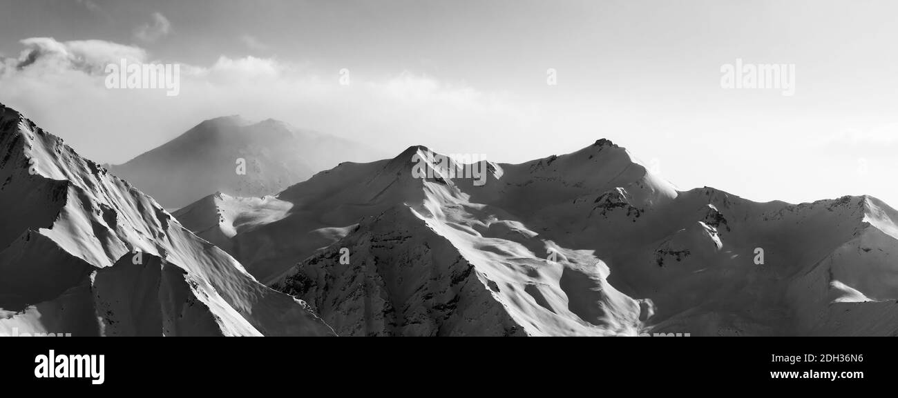 Vista panoramica in bianco e nero sulle montagne innevate del sole in mattina presto nebbia. Montagne del Caucaso in inverno, Georgia, regione Gudauri. Contrasto elevato. Foto Stock