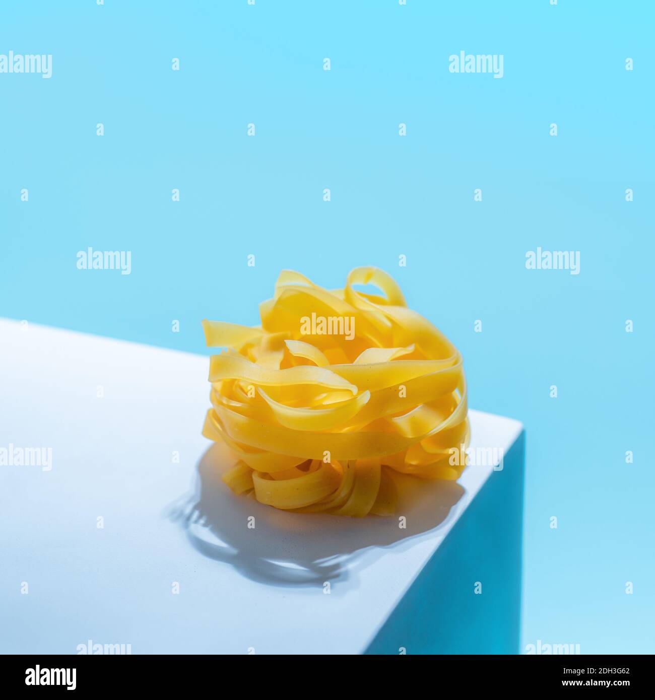 Pasta art con tagliatelle su sfondo blu Foto Stock