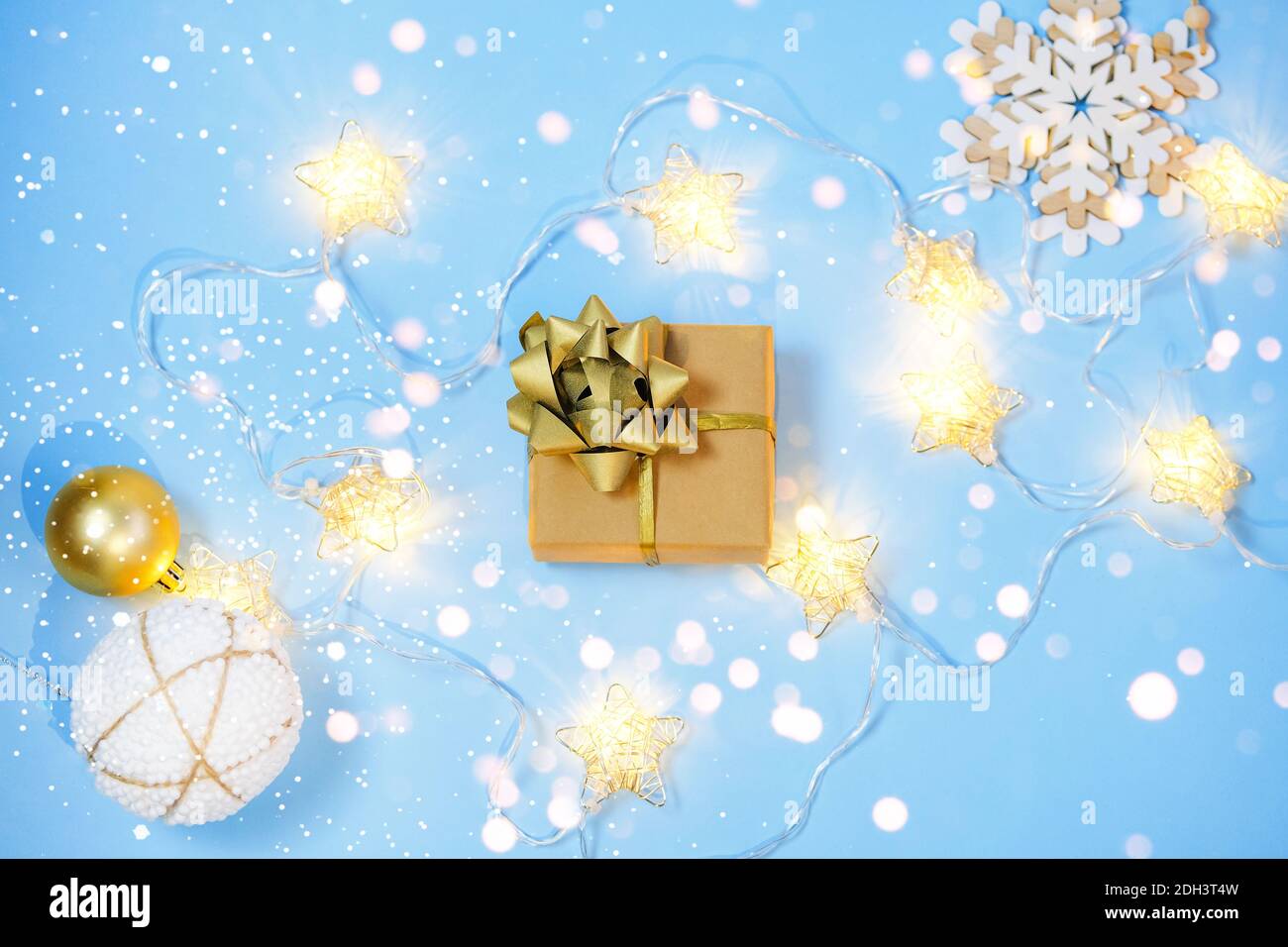 Confezione regalo di Natale avvolta con carta artigianale e luci su sfondo blu bokeh luci. Foto Stock