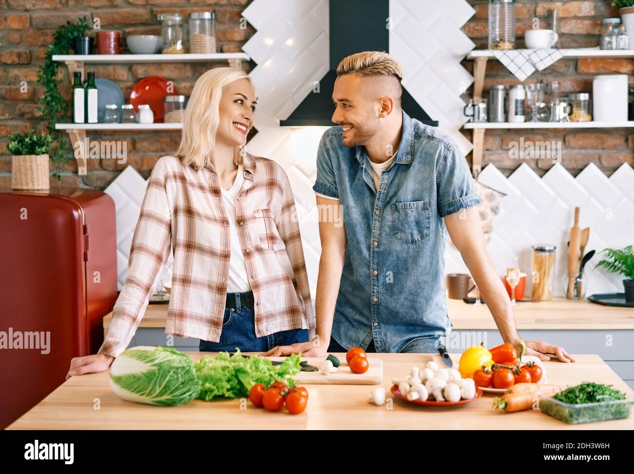 Sorridente giovane coppia che cucinano insieme in cucina a casa Foto Stock