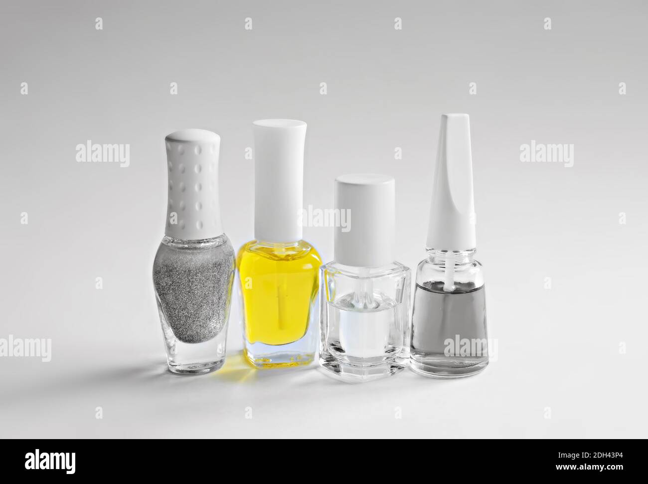 Una serie di prodotti per la cura delle unghie. Bottiglie con vernice per manicure grigia, trasparente e gialla. Colori dell'anno 2021. Foto Stock