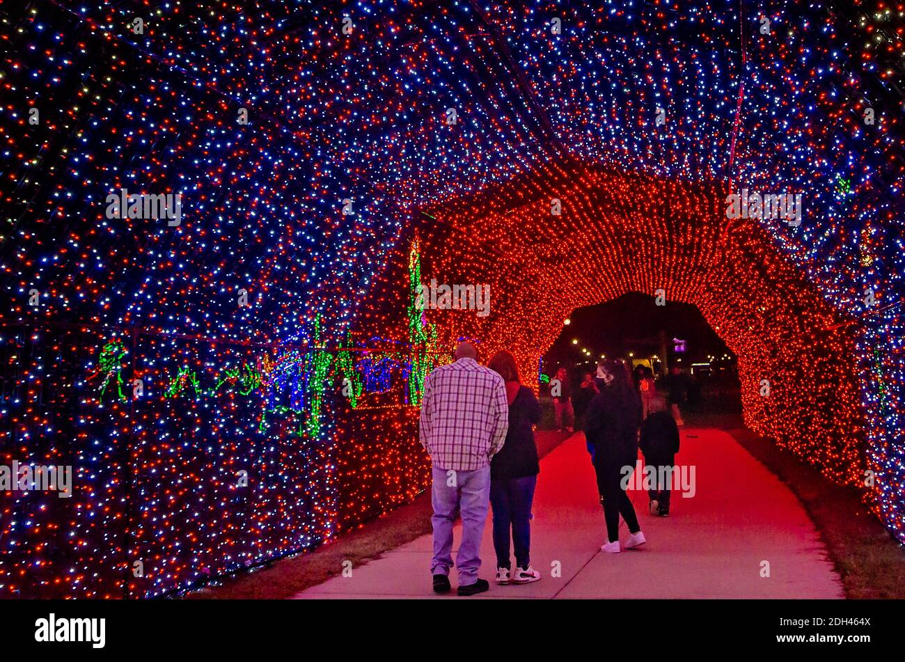 La gente cammina attraverso un tunnel a luci di Natale a LED durante una festa a Jones Park, 5 dicembre 2020, a Gulfport, Mississippi. Foto Stock