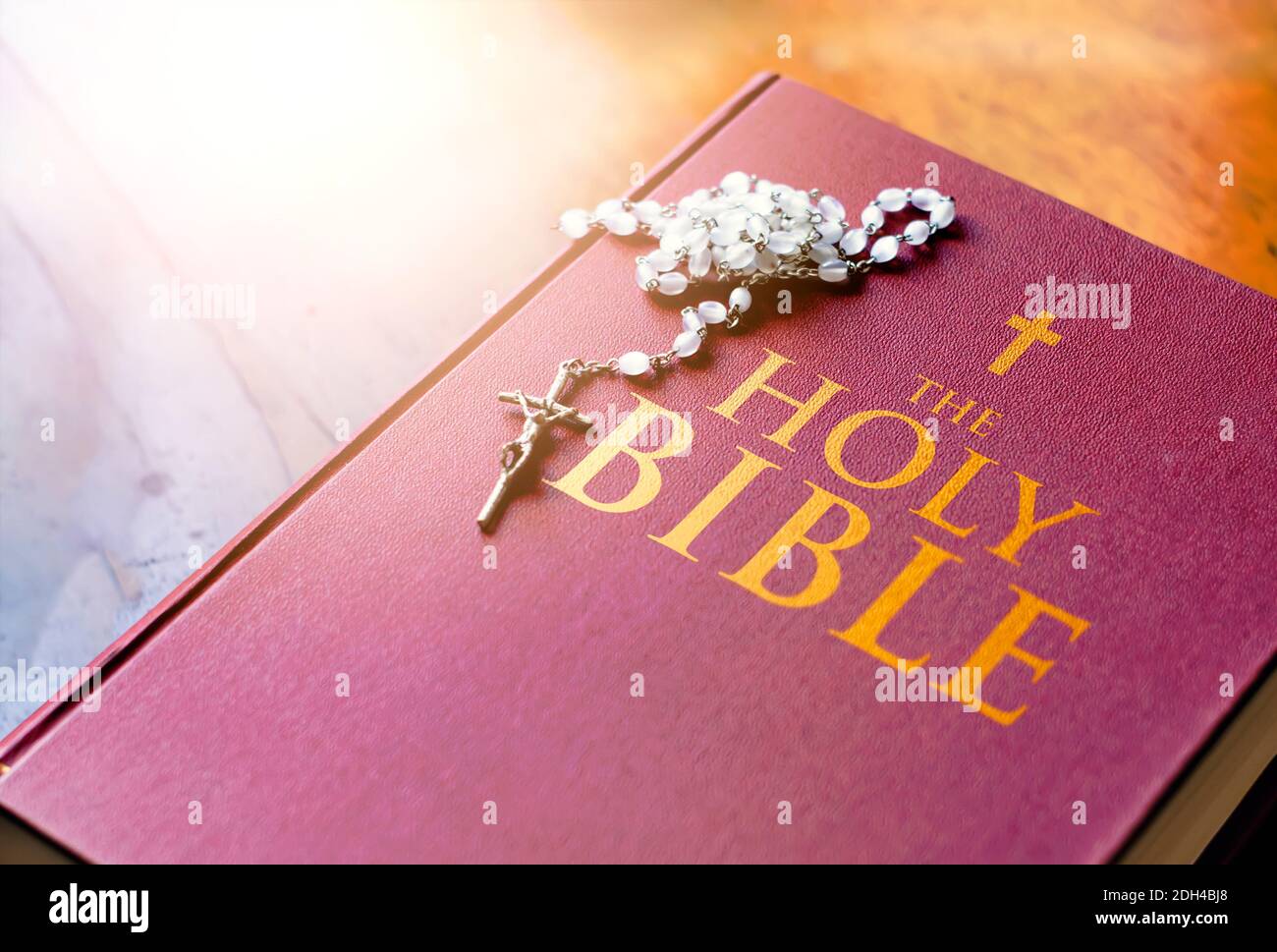 Un rosario di perline bianche con un crocifisso d'argento sopra la copertina del libro sacro chiuso della bibbia. Religione e speranza. Oggetti religiosi per pregare Foto Stock