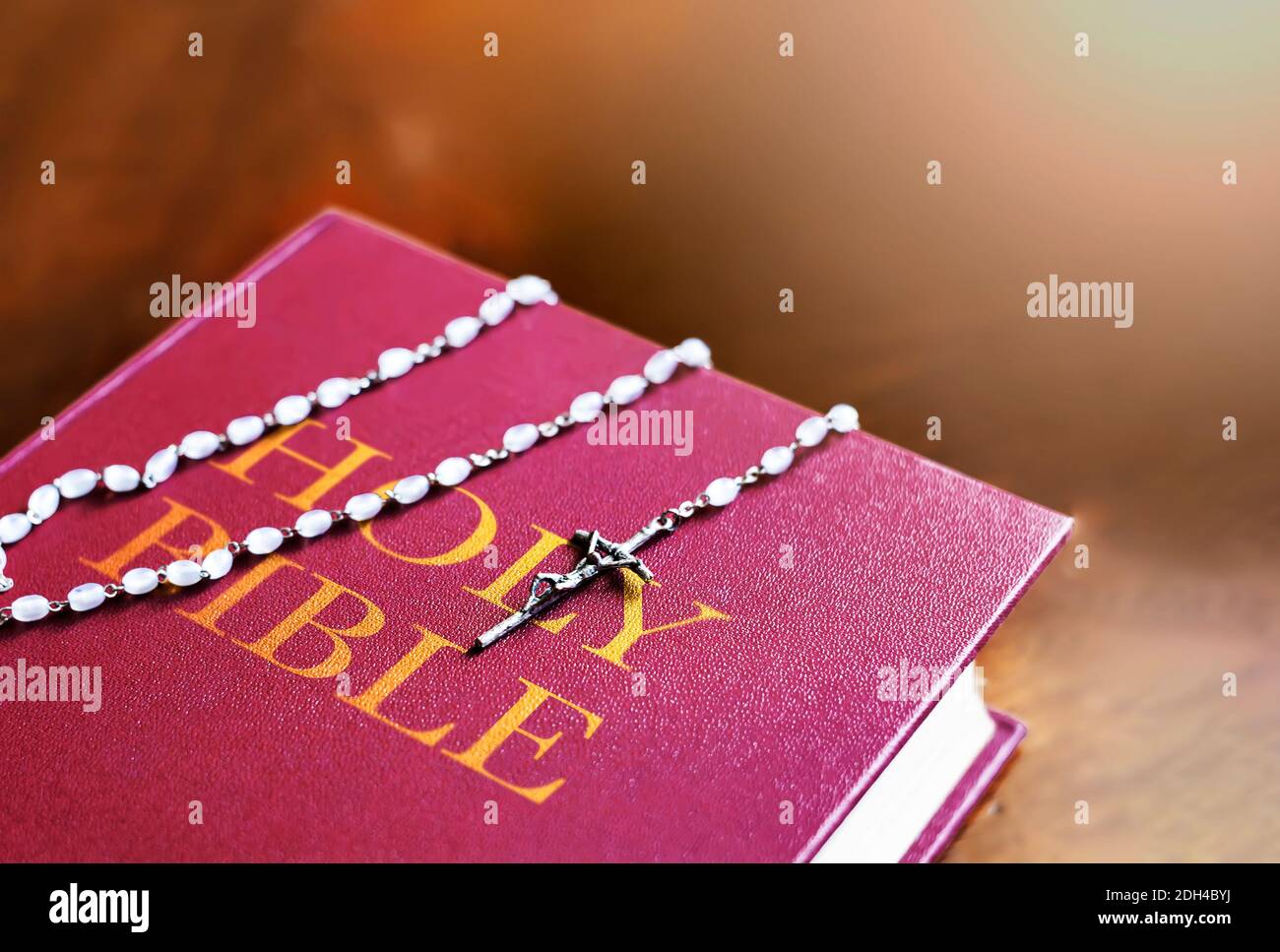 Un rosario di perline bianche con un crocifisso d'argento sopra la copertina del libro sacro chiuso della bibbia. Religione e speranza. Oggetti religiosi per pregare Foto Stock