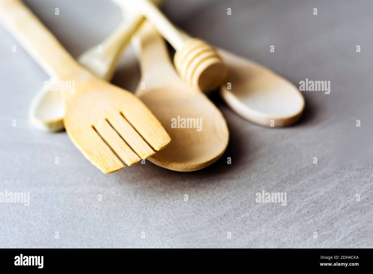 Gruppo di utensili da cucina in legno disposti su un tavolo in marmo grigio. Fuoco selettivo sulla forchetta da carving. Foto Stock