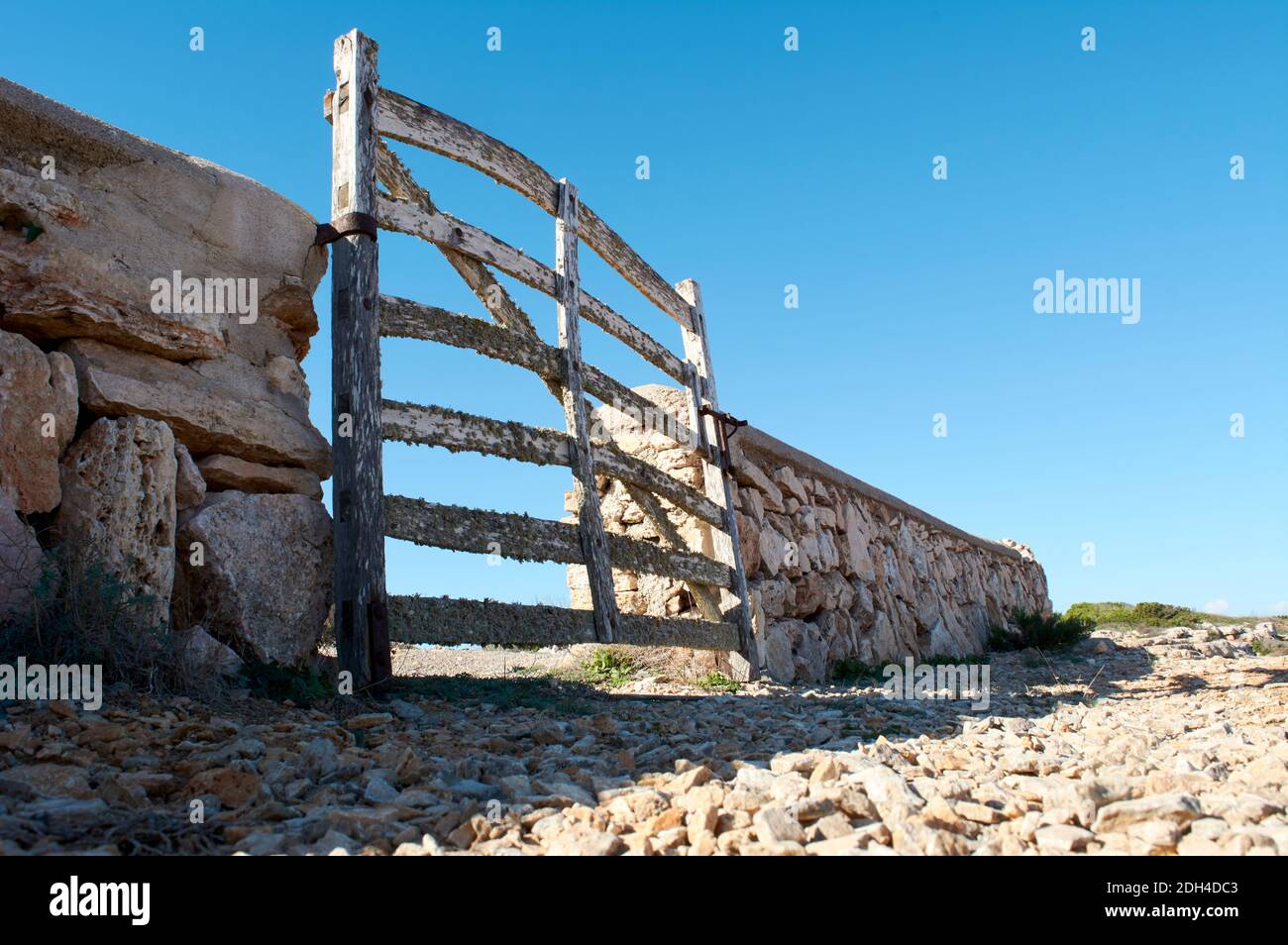 Vista dal suolo, di tipica porta in legno, con licheni, in muratura in pietra accanto alla strada, con bel cielo blu sulla foresta mediterranea, mallorc Foto Stock